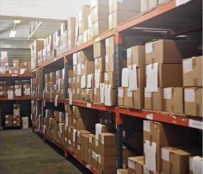 Shelving units in a warehouse fully stocked with cardboard boxes.